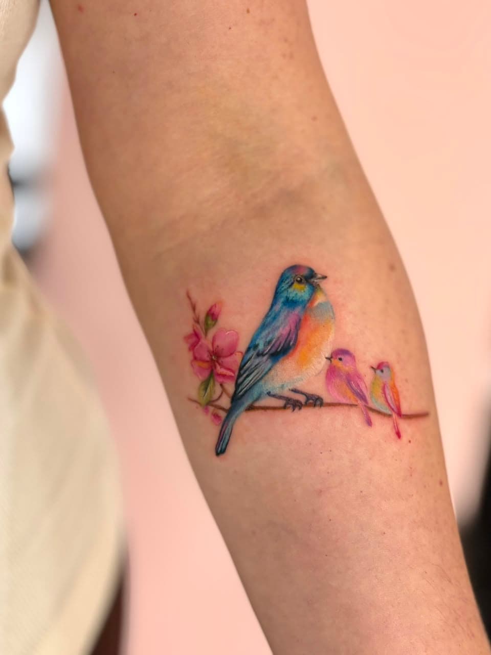 Tatuagem colorida de pássaros em um galho